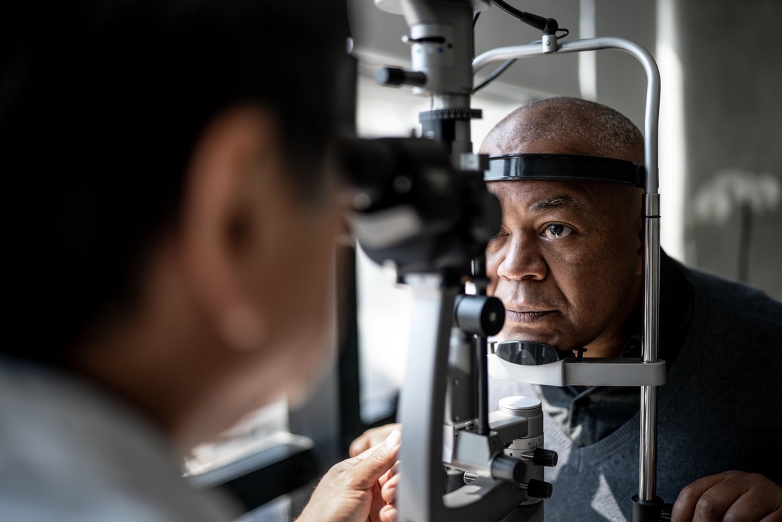 Eye care patient during examination, looking into exam machine