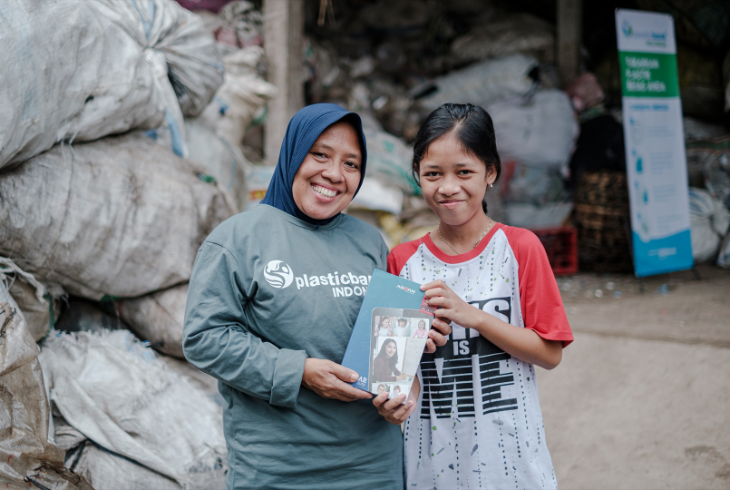 Woman and girl stand in front of bags of collected plastic