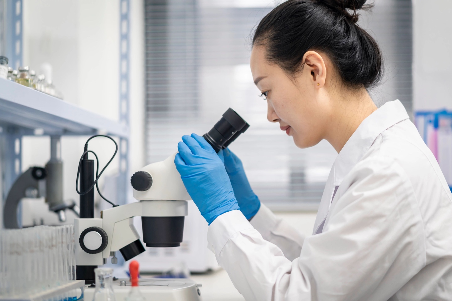 Woman in lab looking into microscope