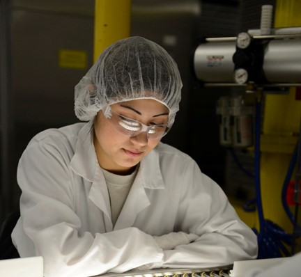 Woman in lab coat, hair net, & goggles