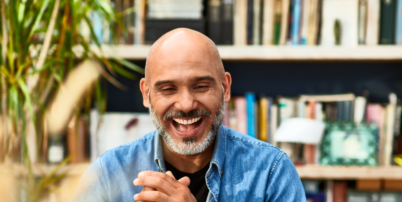 Smiling man looking at a laptop and wearing a blue shirt