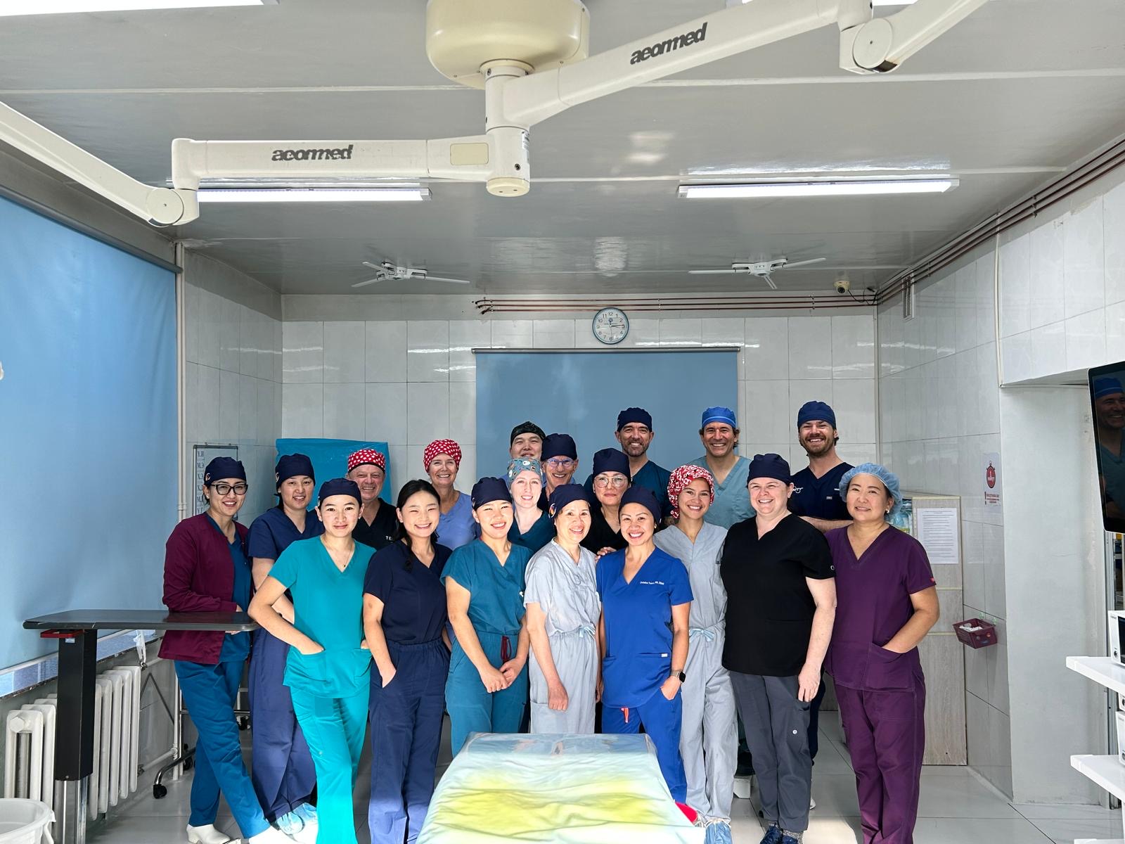 Team of volunteers standing in group for photo in otherwise empty operating room