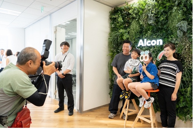 植物がたくさん置かれた明るい部屋で、カメラマンが面白いメガネをかけた子供の写真を撮っています。