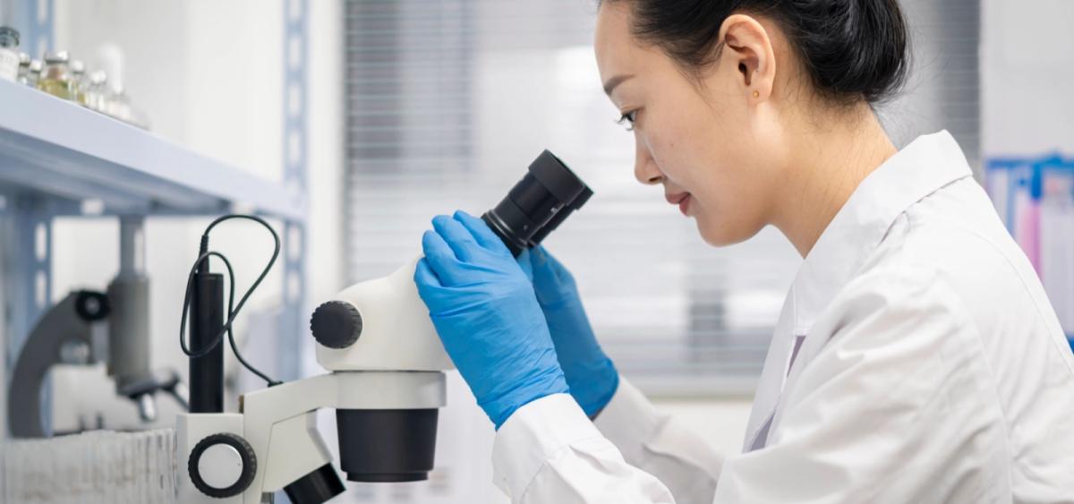 Woman in lab looking into microscope