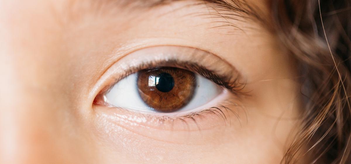 Close up image of child's eye with brown iris and brown curly hair