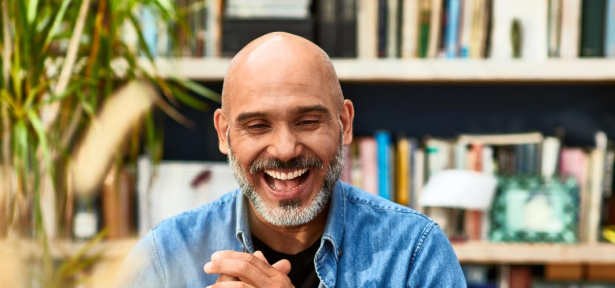 Smiling man looking at a laptop and wearing a blue shirt