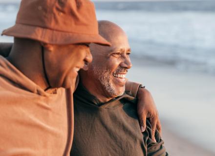 Father and adult son laughing and sharing a moment at the beach