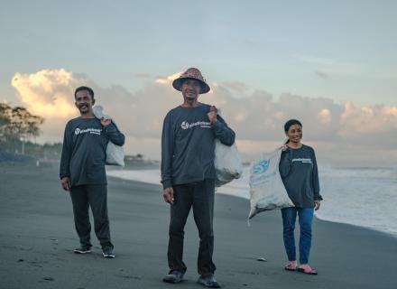 Three people in Indonesia collecting plastic along beach