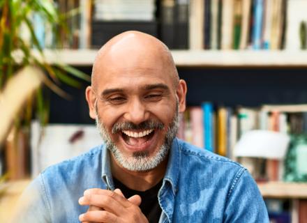 Smiling man looking at a laptop and wearing a blue shirt