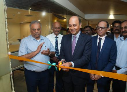 Five men in business dress smiling. One is cutting a ribbon on the new Aravind Retina Centre of Excellence