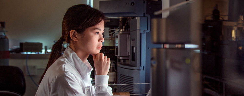 A woman researcher in a lab, sideline, studying her output.